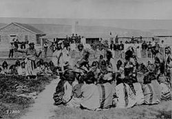 Shoshone Indians at Fort Washakie, Wyoming Indian Reservation. Some of the Indians are dancing as soldiers are watching, 1892