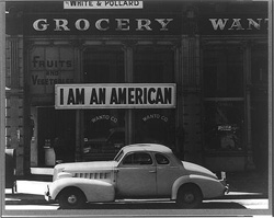 Dorothea Lange photograph of a Japanese American business owner hung this banner outside his business the day after the Pearl Harbor attack. The owner was soon “relocated” to an internment camp.